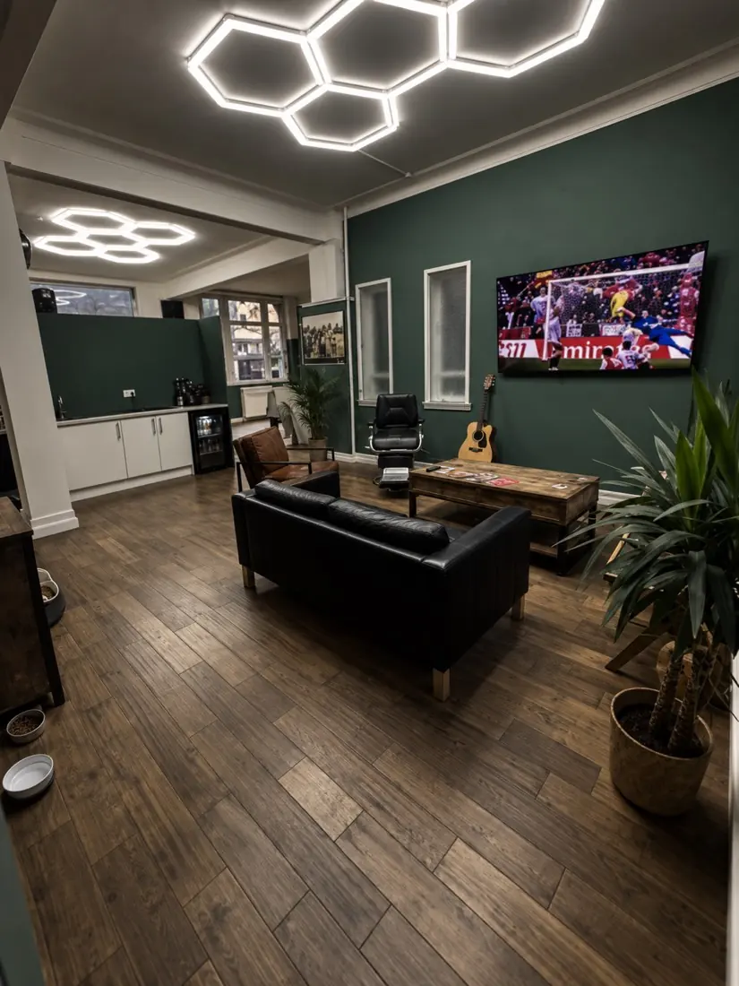 Waiting area with a leather sofa, the telly on and Sally’s bowls by the wall